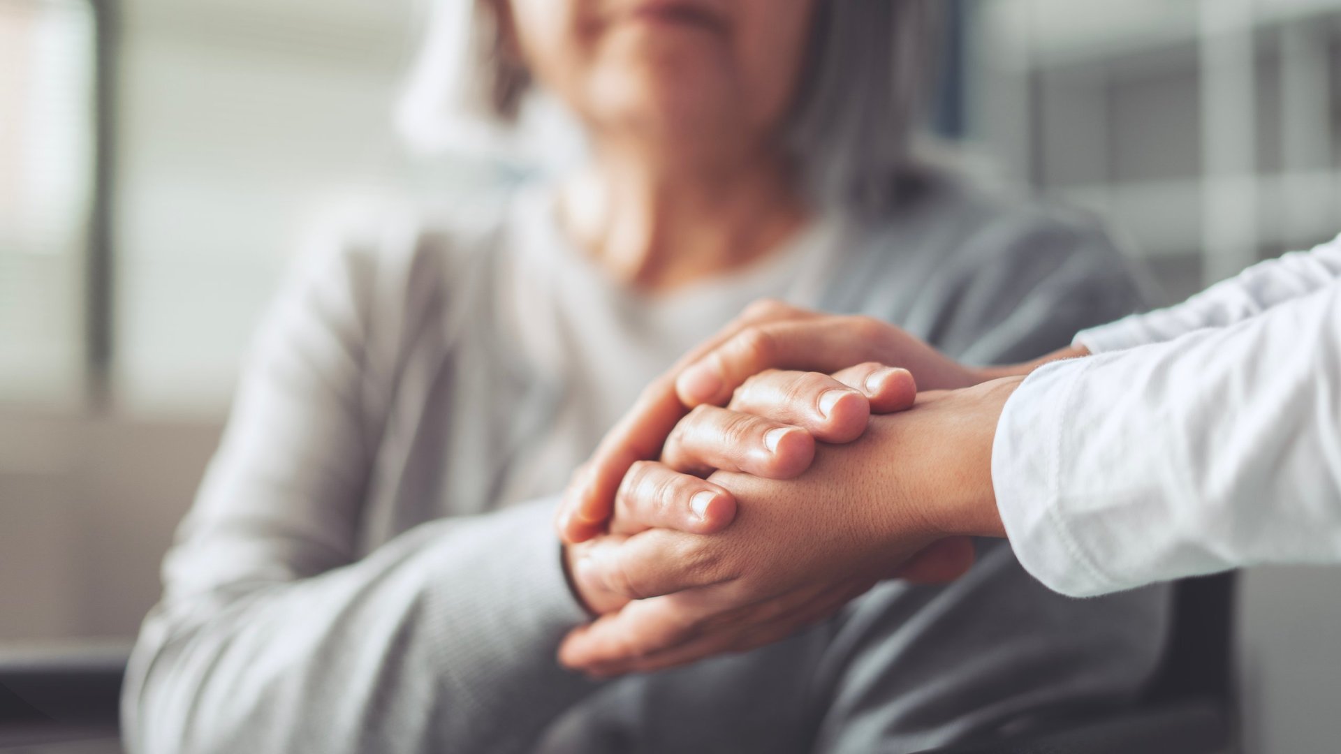 Caregiver holding hands with elderly resident